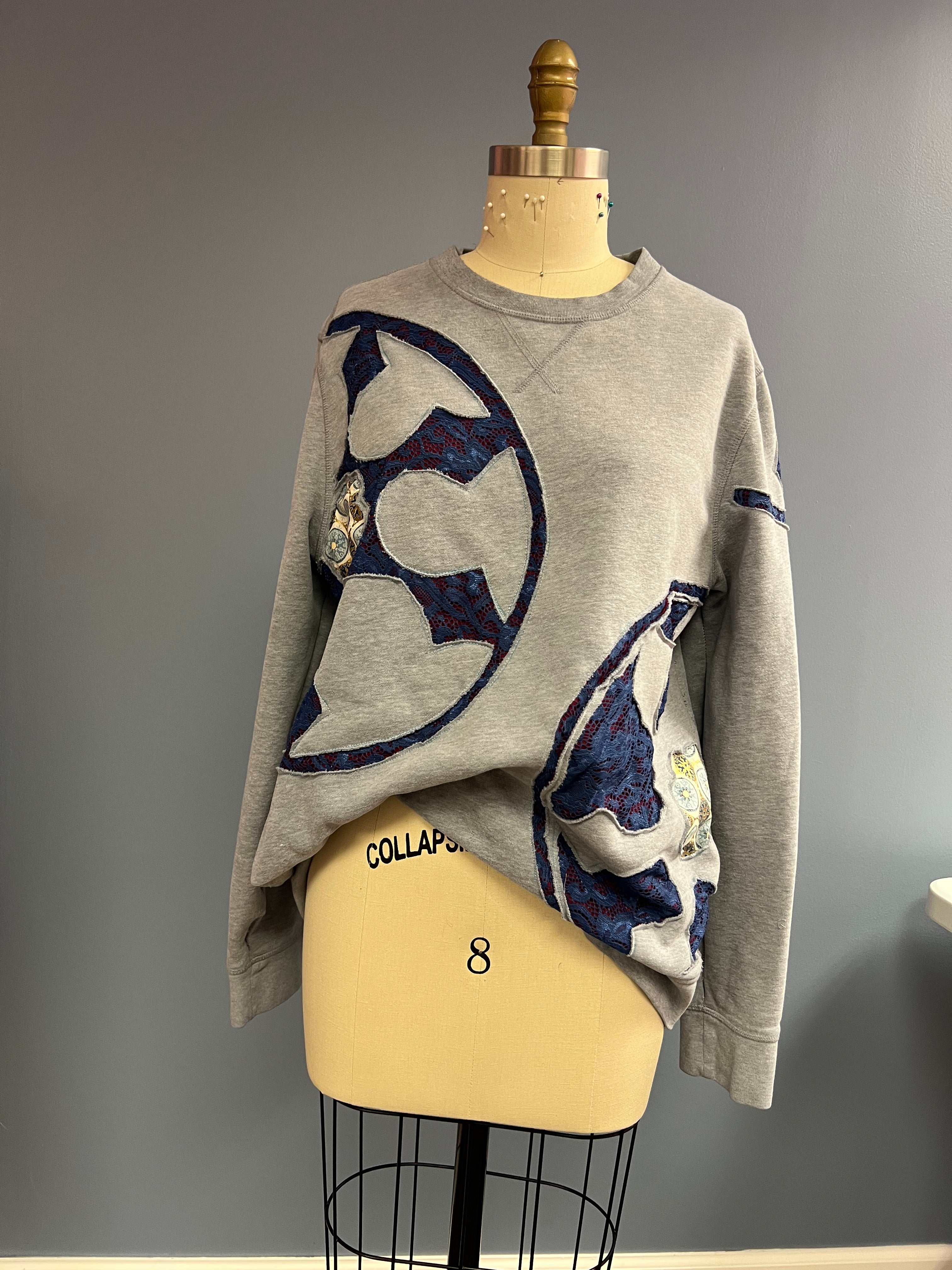Gray sweater with blue and white abstract designs on a mannequin against a gray background